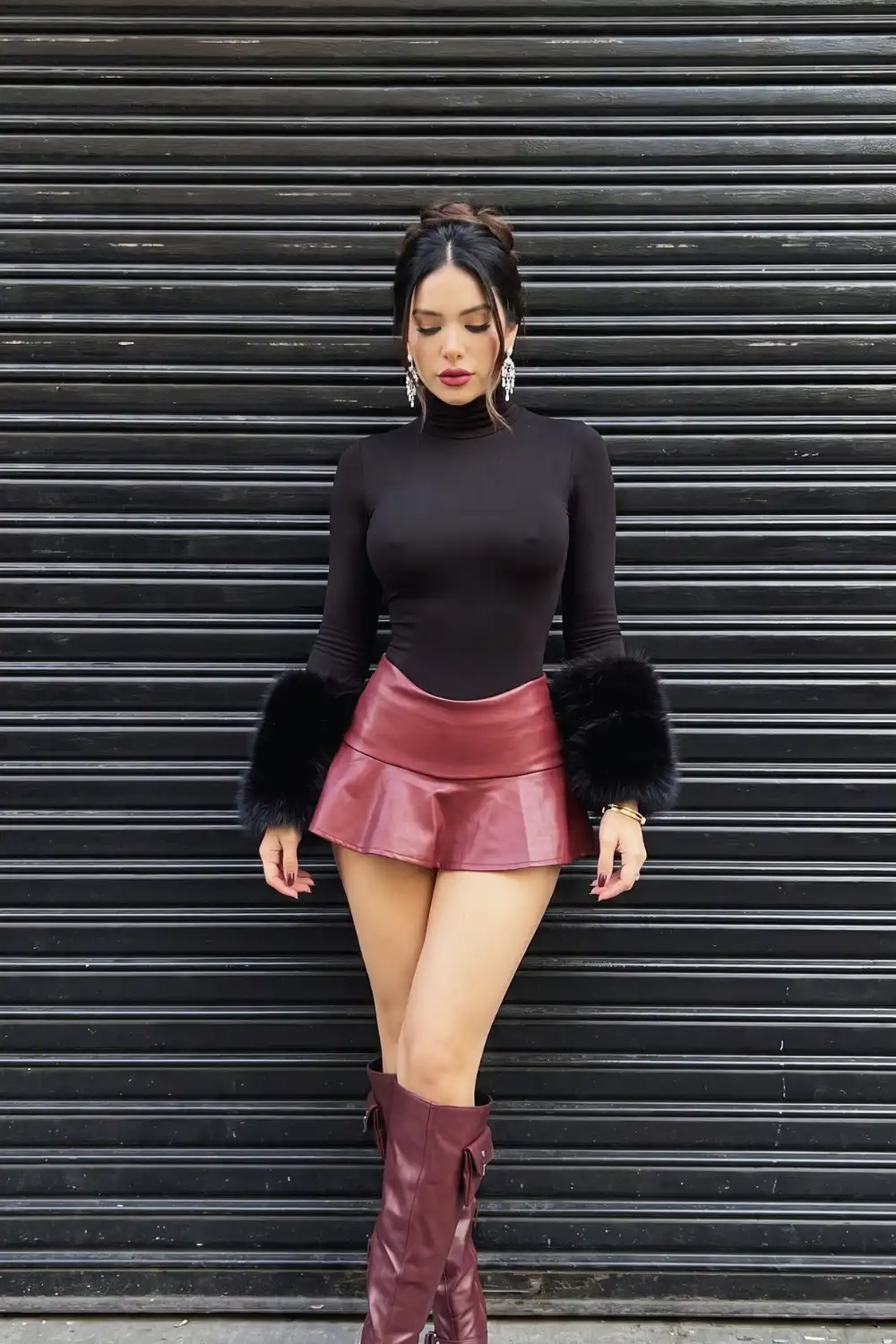 Woman in black turtleneck fur cuff top with burgundy leather flare mini skirt and knee high boots