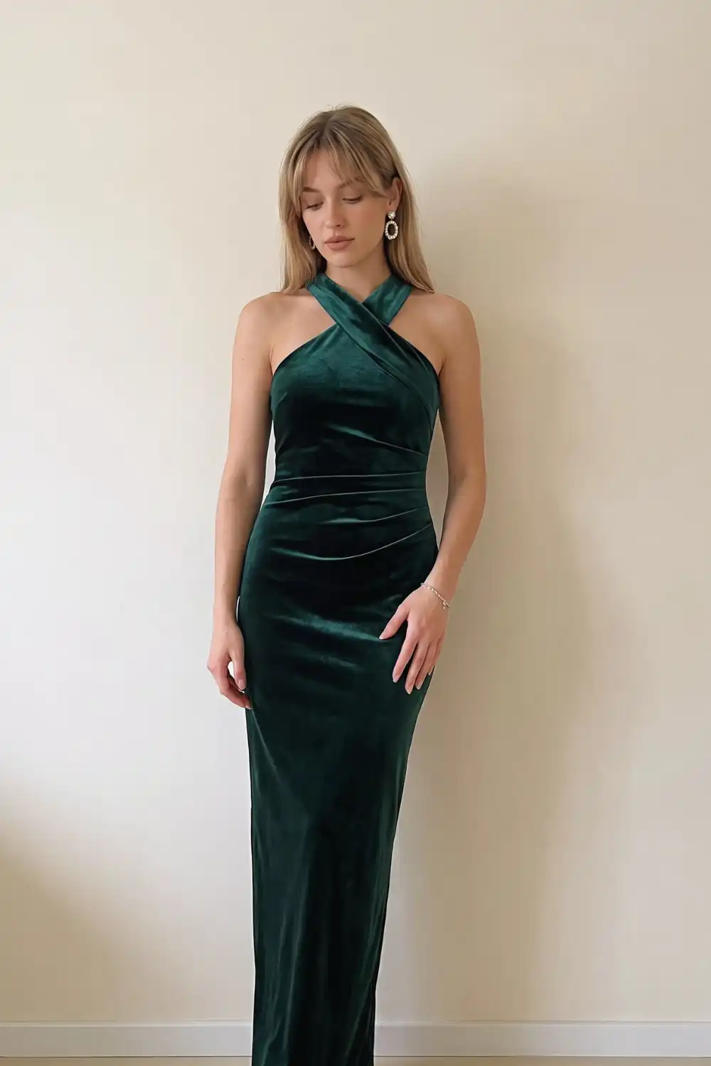 Woman in emerald green velvet halter neck maxi dress