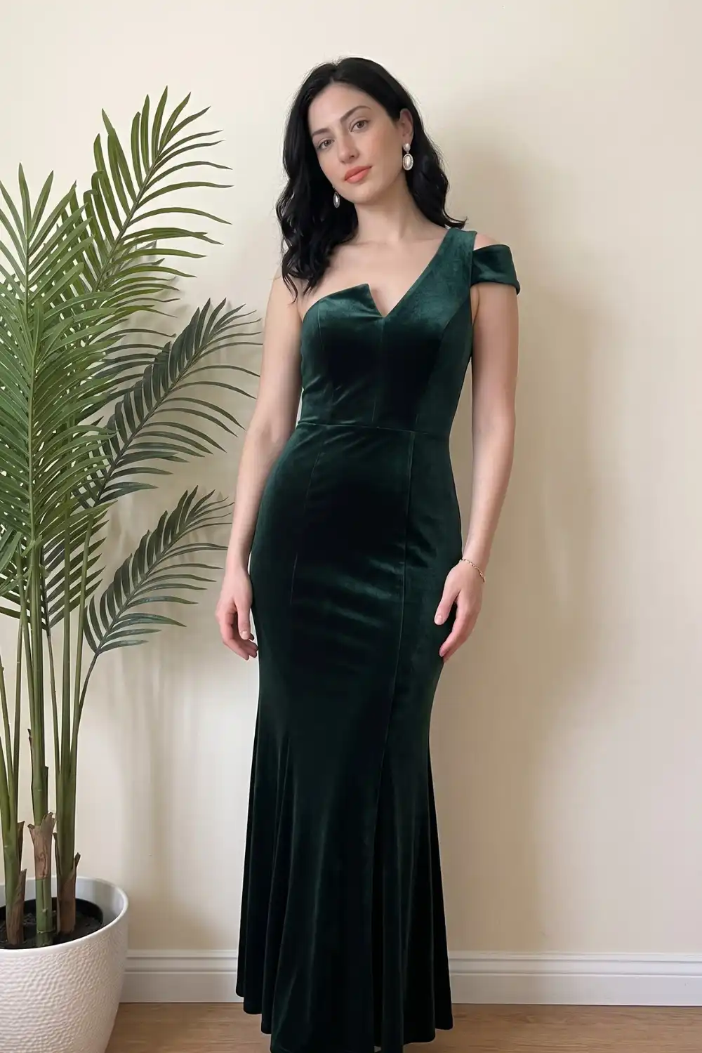 Woman in emerald green velvet off shoulder mermaid maxi dress