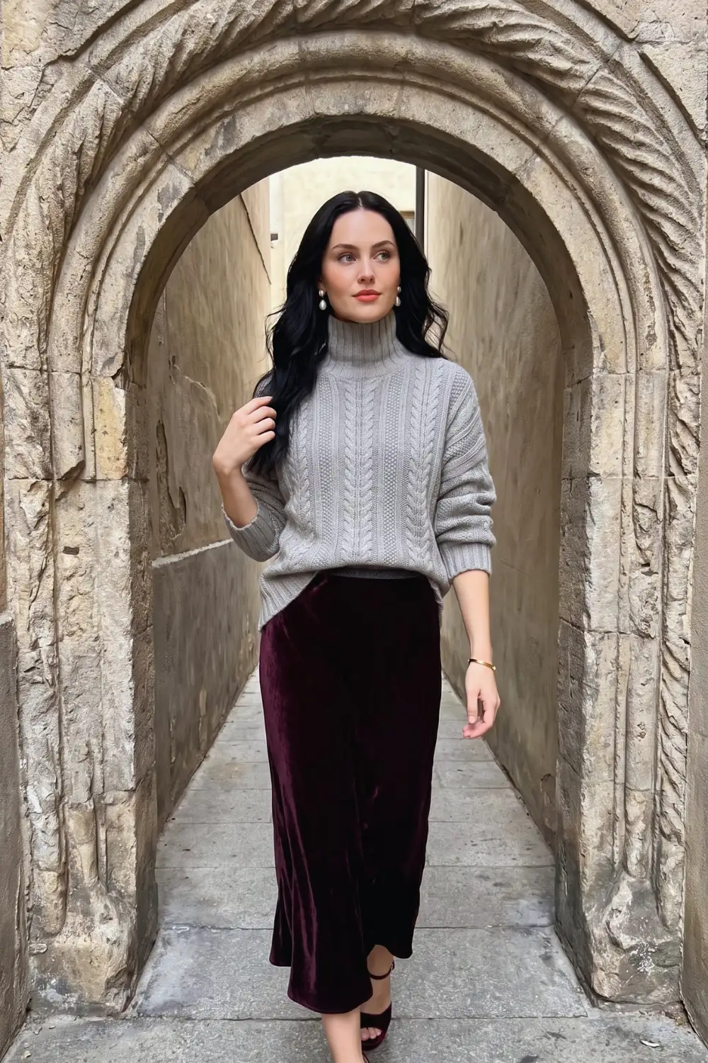 Woman in grey oversized cable knit turtleneck with burgundy velvet maxi skirt