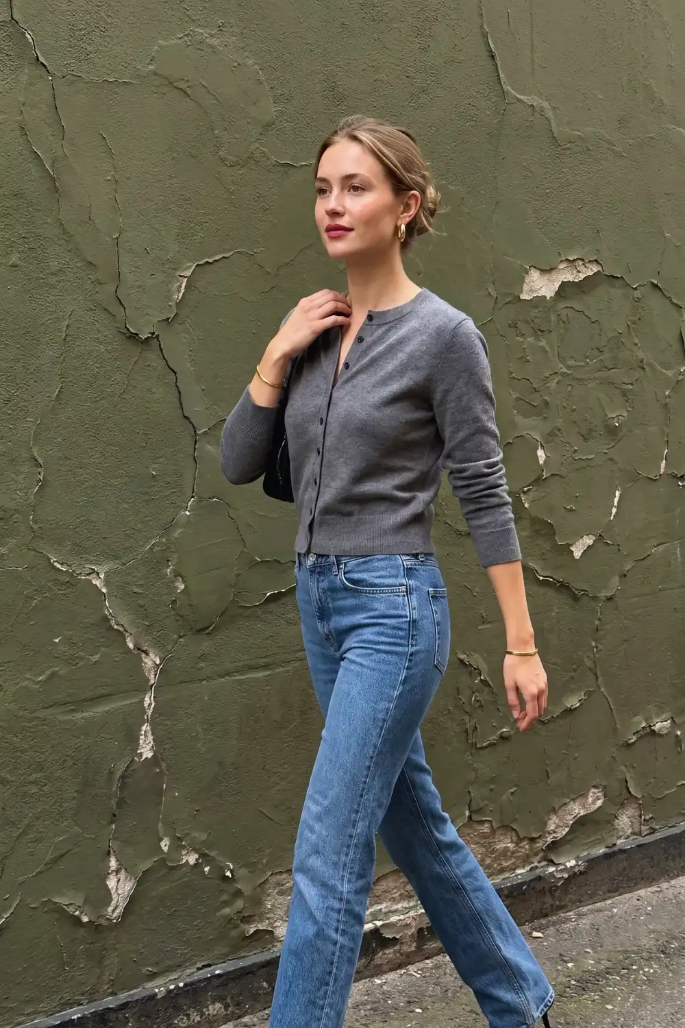 Woman in grey fitted crew neck cardigan with mid blue straight leg jeans