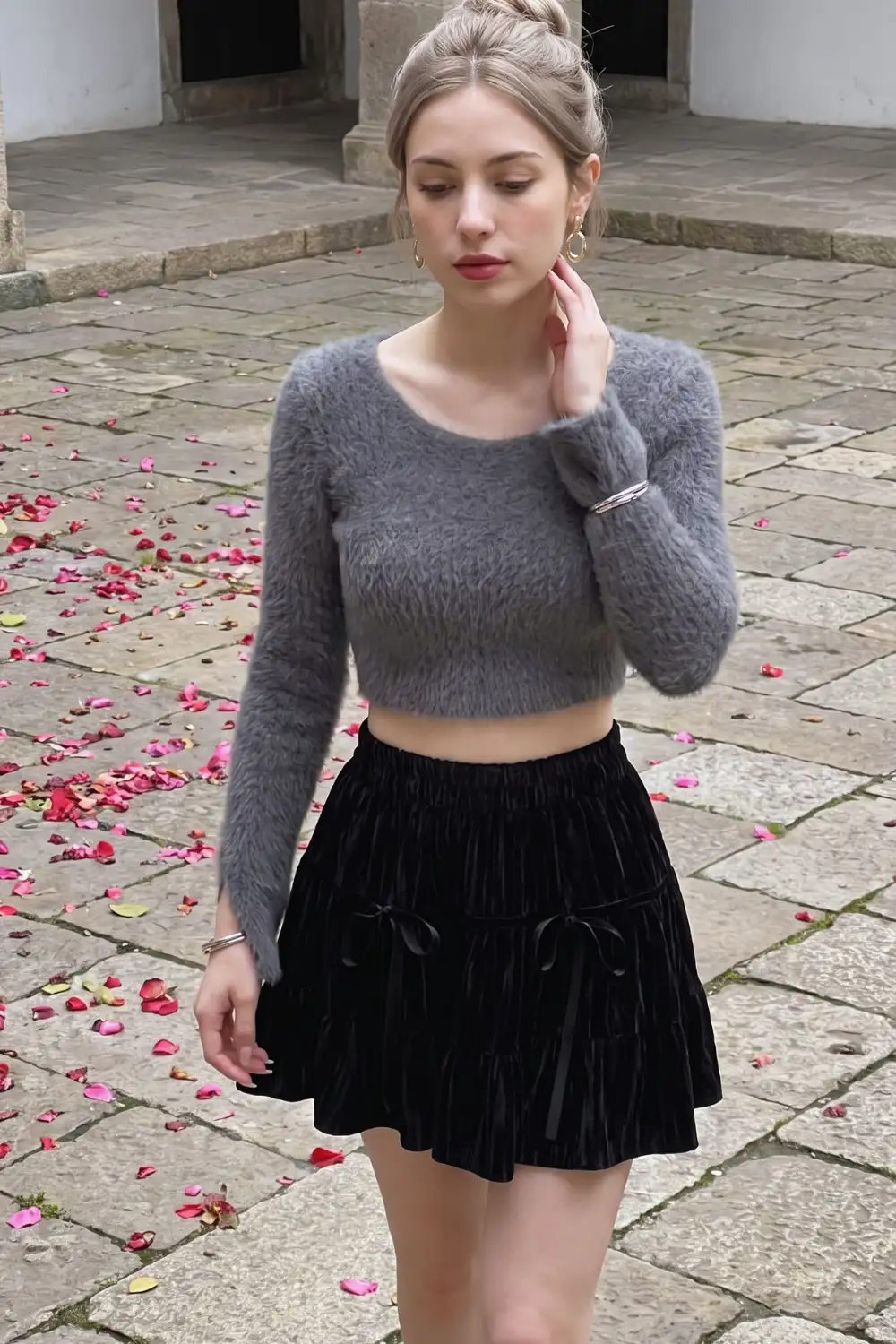 Woman in grey fluffy crop sweater with black velvet bow detail pleated mini skirt