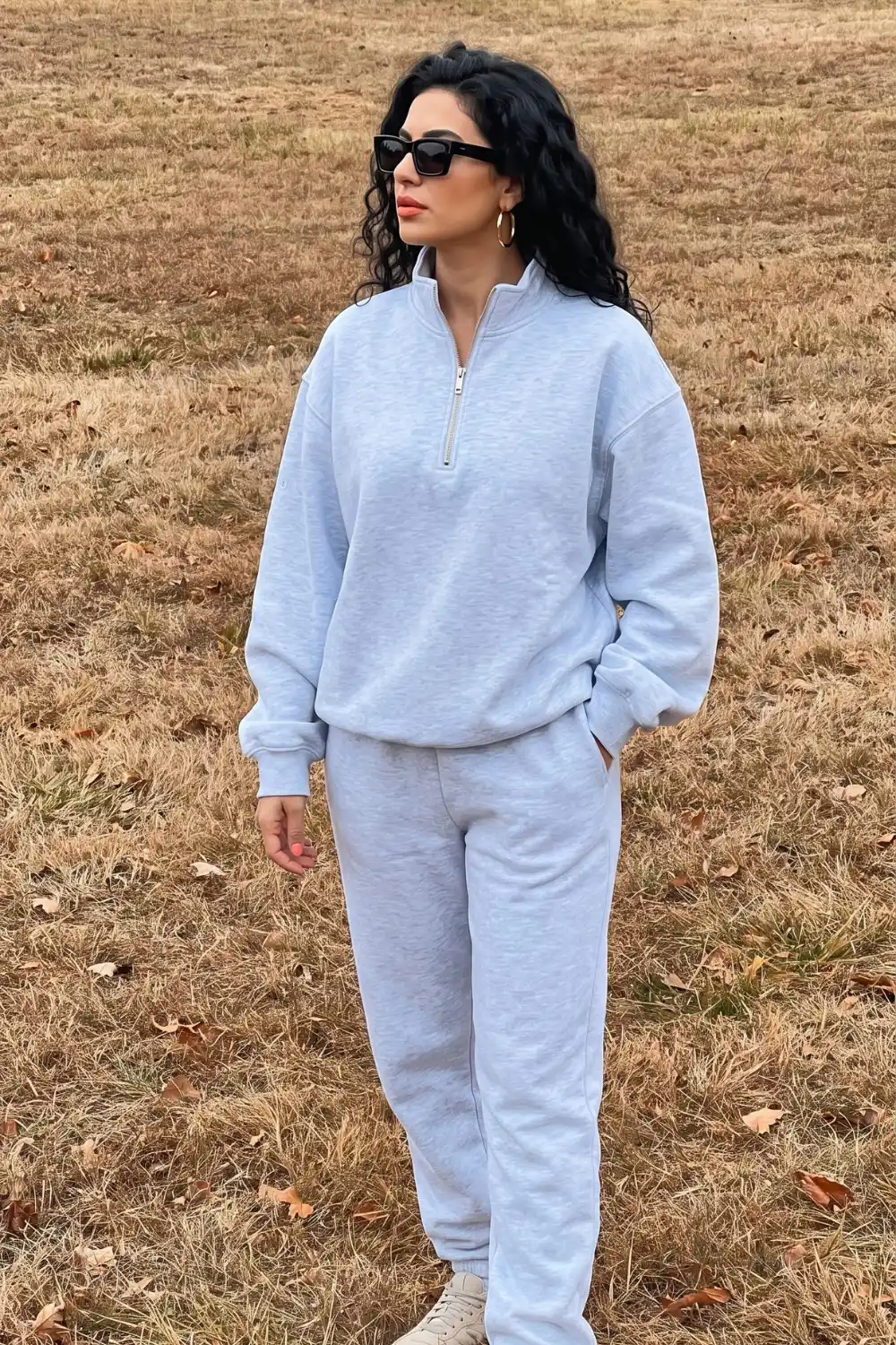 Woman wearing light grey oversized quarter-zip sweatshirt with matching joggers