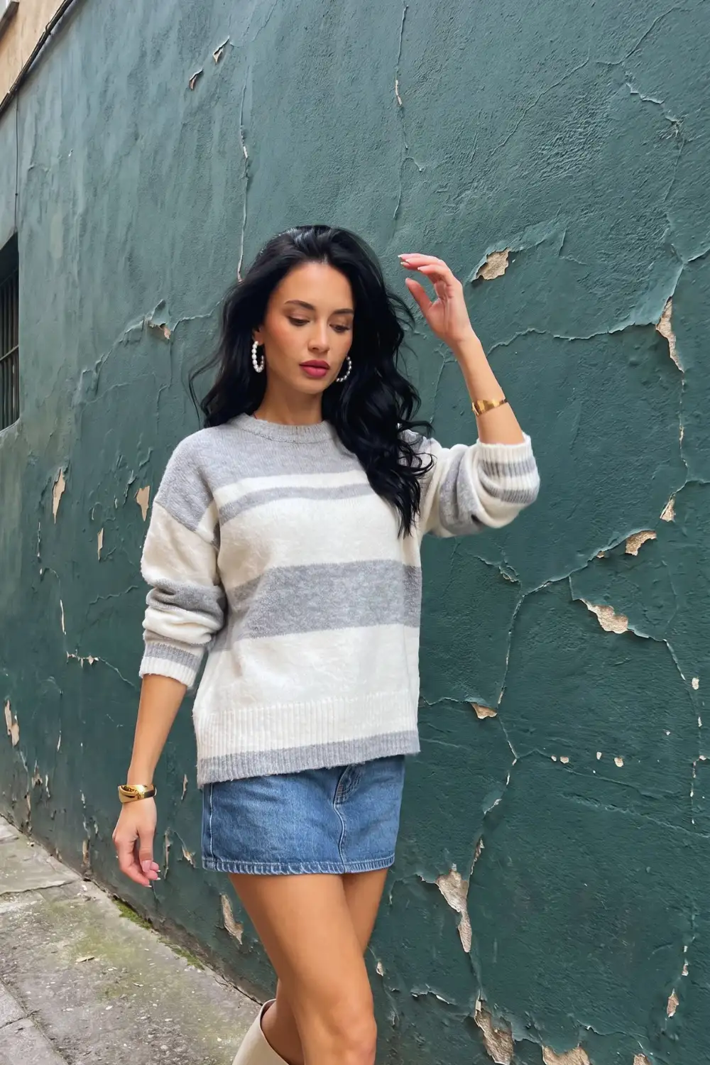 Woman in grey cream stripe fluffy oversized sweater with denim mini skirt and knee high boots