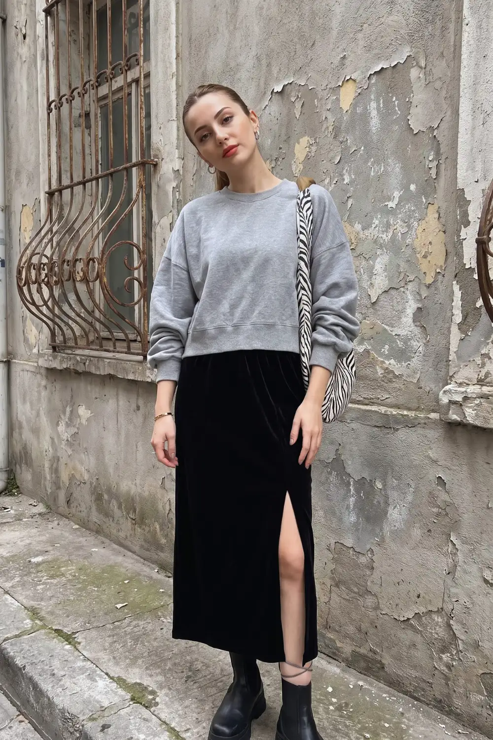 Woman in grey crop sweatshirt with black velvet maxi skirt and chelsea boots