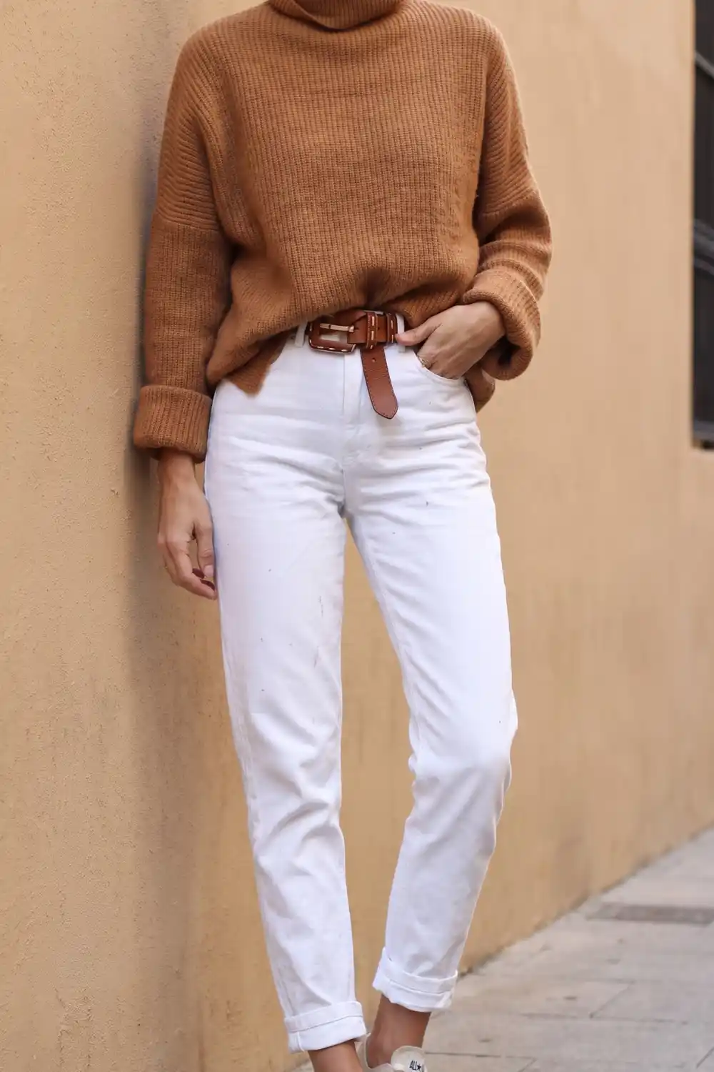 Woman wearing camel turtleneck knit sweater with white mom jeans