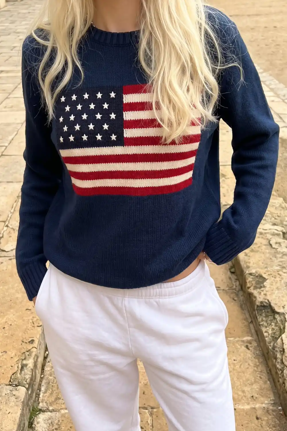 Woman wearing navy American flag knit sweater with white trousers