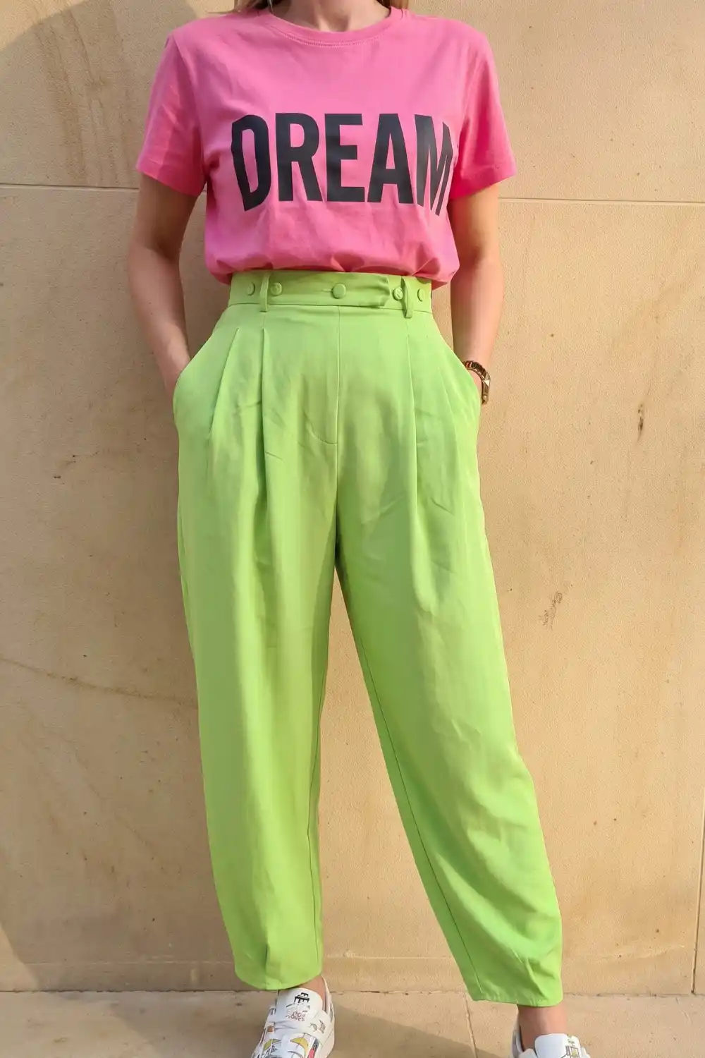 Woman wearing pink Dream graphic tee with lime green high waist pleated trousers