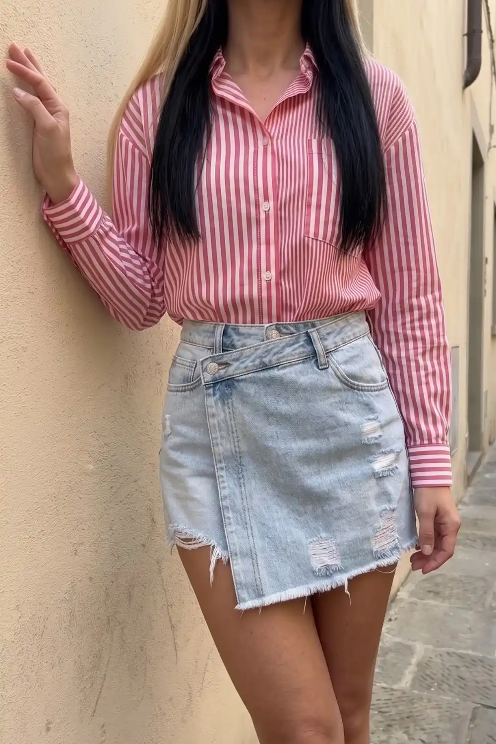 Woman wearing pink and white striped oversized shirt with light blue ripped denim mini skirt