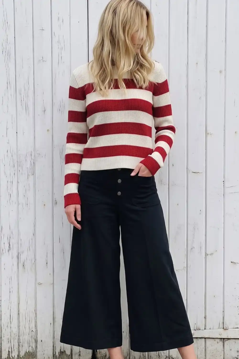 Woman wearing red and cream striped knit sweater with black wide leg crop pants
