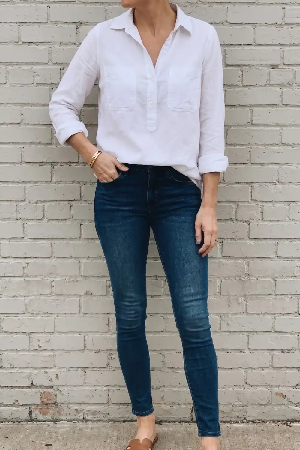 Woman wearing white linen half button popover shirt with dark blue skinny jeans