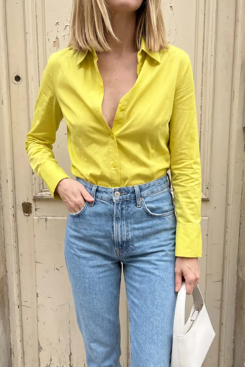 Woman wearing yellow fitted button-up shirt with light blue straight leg jeans