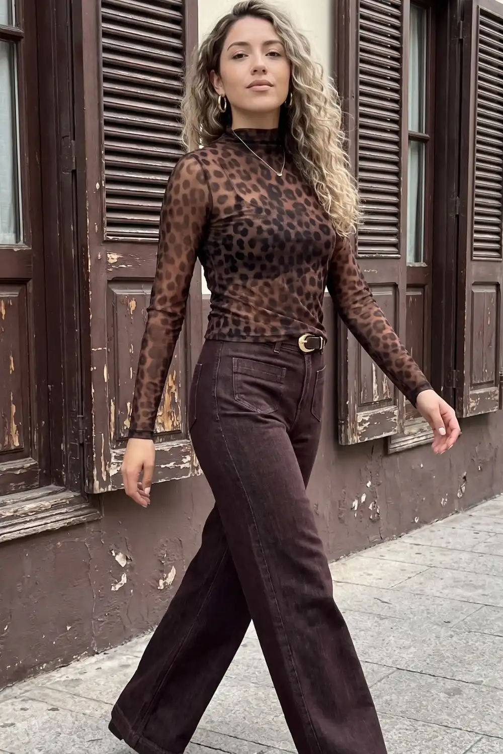 Woman in brown leopard mesh turtleneck top with dark brown wide leg belted jeans