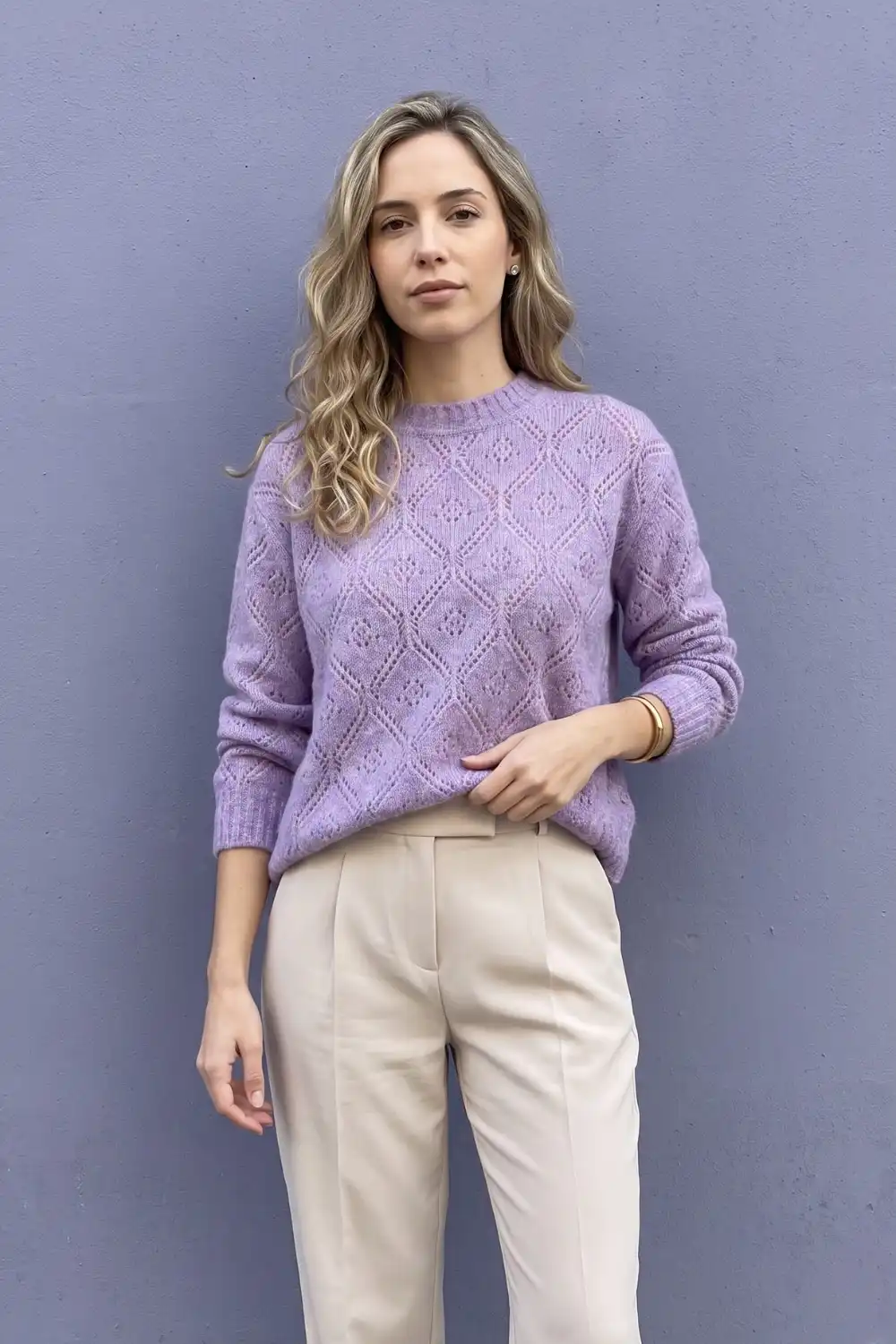 Woman in lilac diamond pointelle knit sweater with cream straight trousers