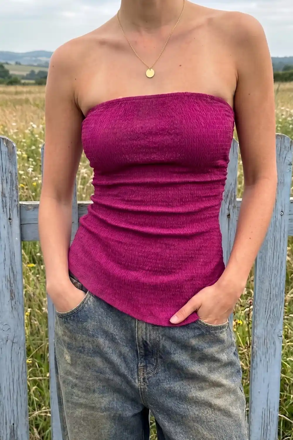 Woman wearing magenta ruched tube top with jeans