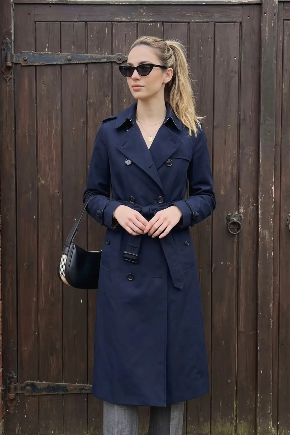 Woman in camel double-breasted trench coat with black mini dress and knee high boots