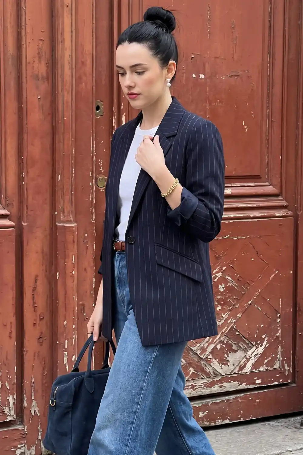 Woman wearing navy pinstripe oversized blazer with white tee and light wash jeans