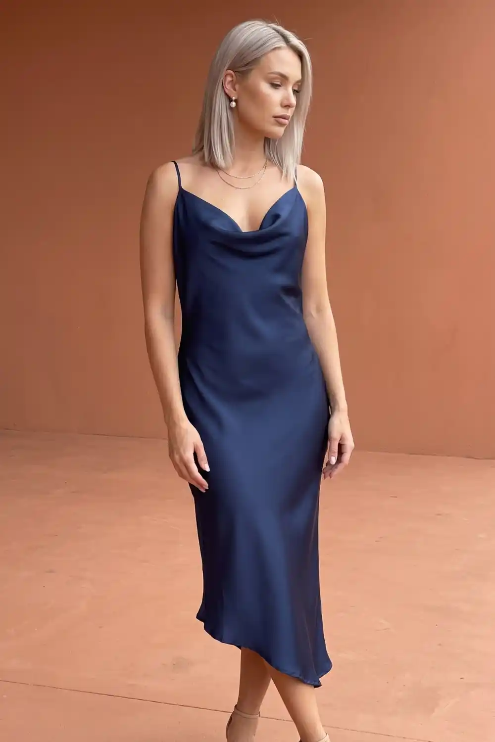 Woman wearing navy blue satin cowl neck slip midi dress