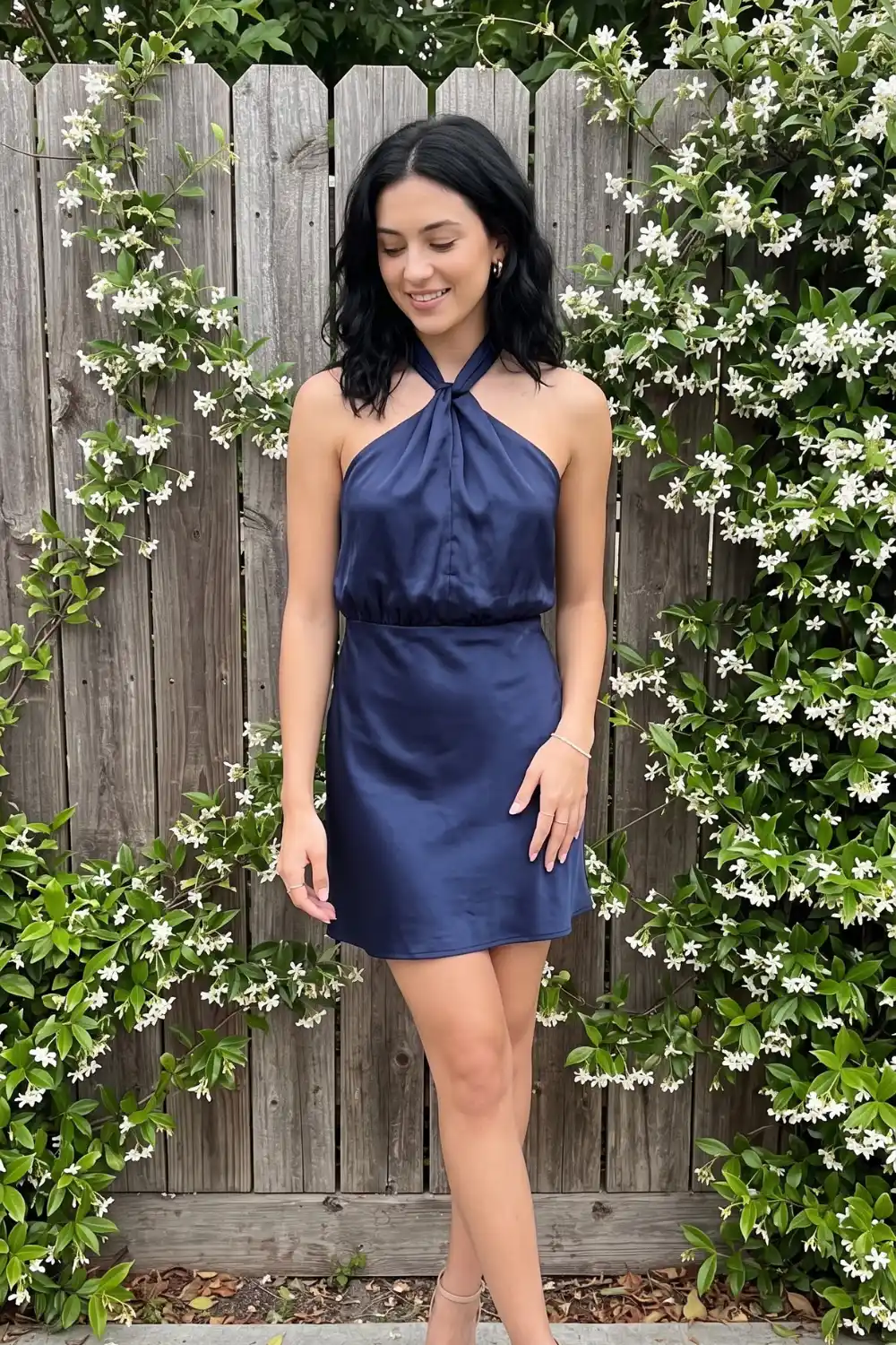 Woman wearing navy blue satin twist halter neck mini dress