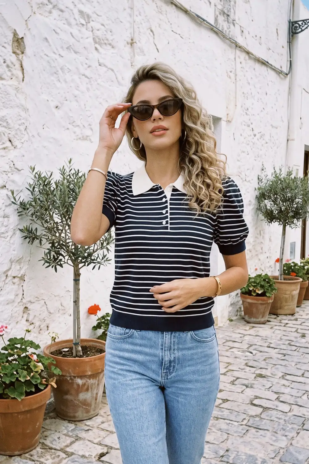 Woman in navy white stripe knit puff sleeve polo top with blue jeans