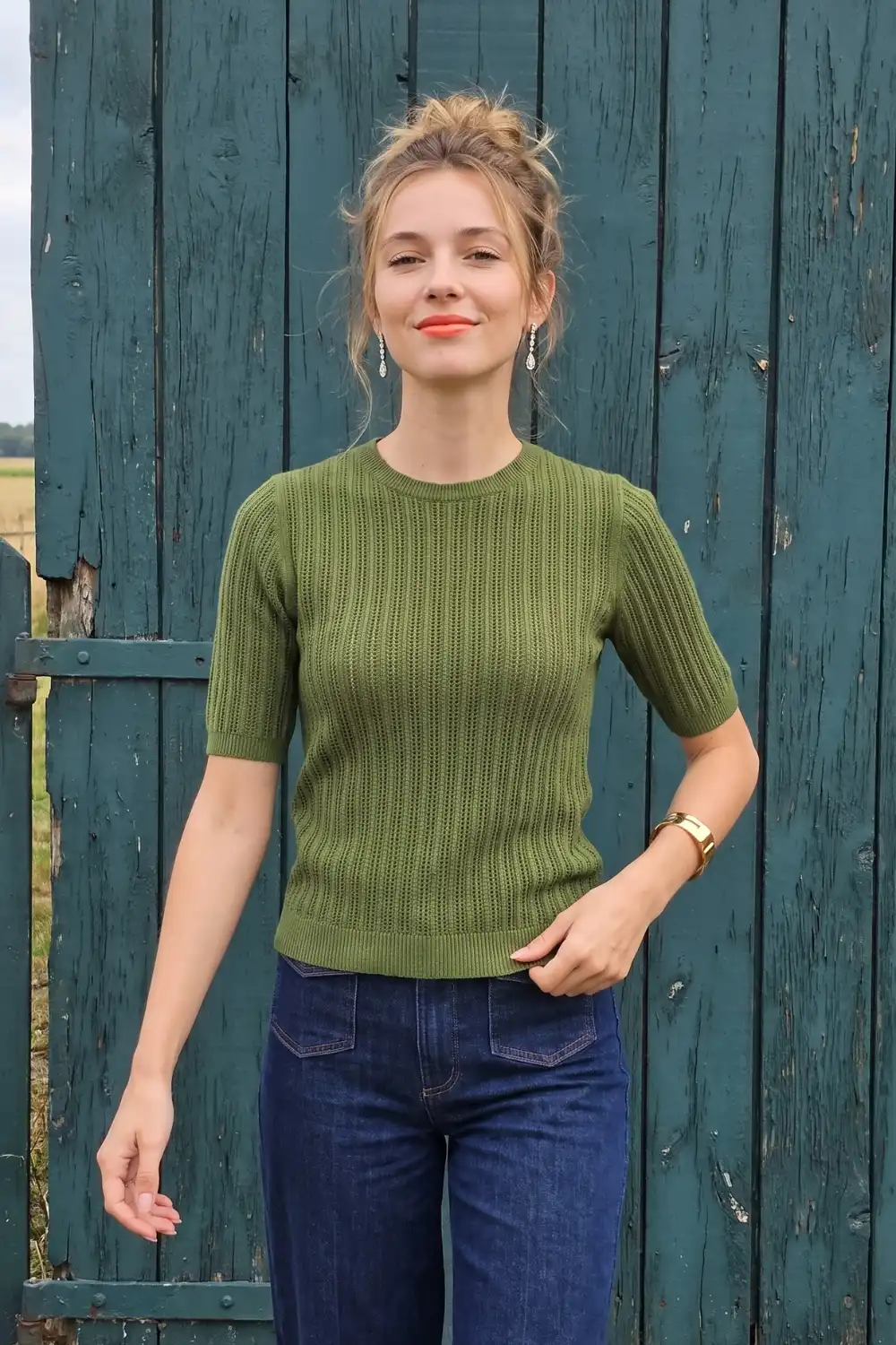 Woman in olive green short sleeve pointelle knit top with dark wash wide leg jeans