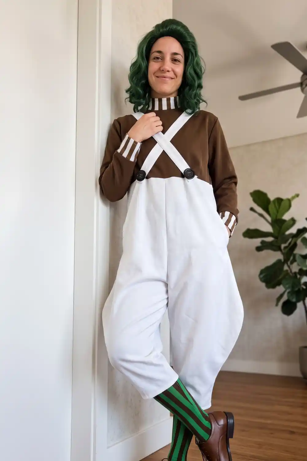 Woman dressed as Oompa Loompa in brown turtleneck white overalls and green wig
