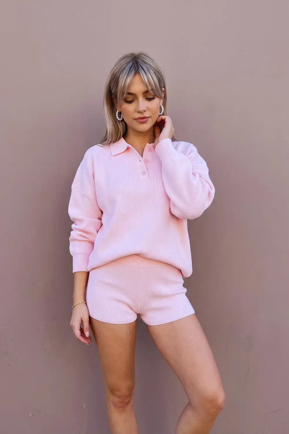 Woman in baby pink ribbed knit polo collar oversized sweater with matching mini shorts set