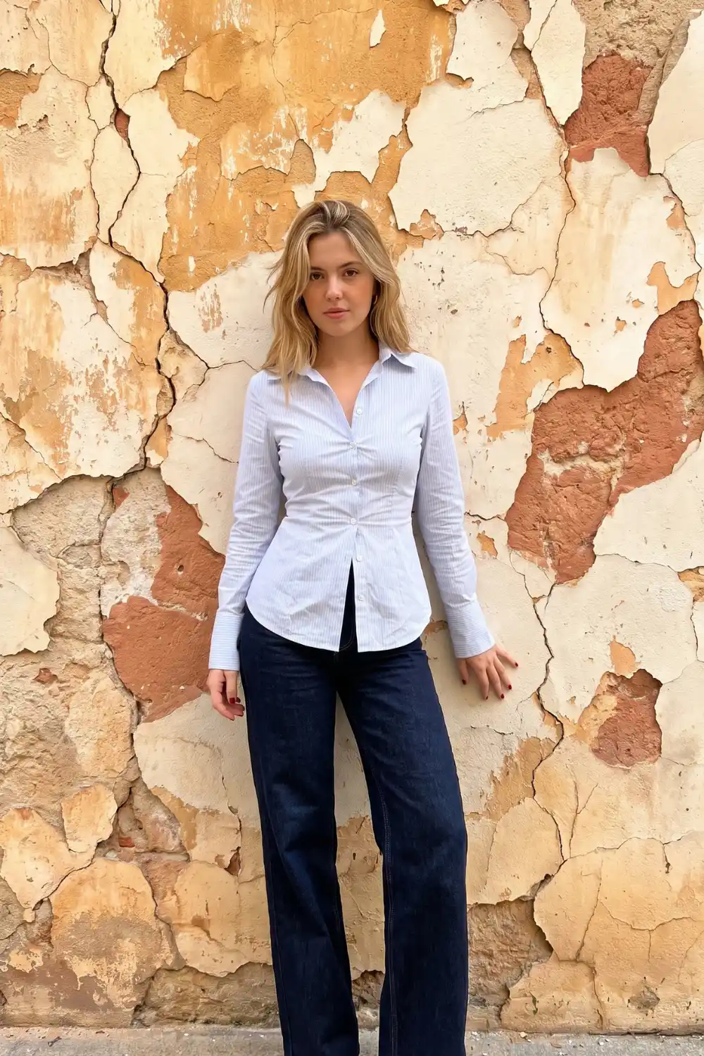 Woman wearing white blue pinstripe fitted button down shirt with dark wash wide leg jeans