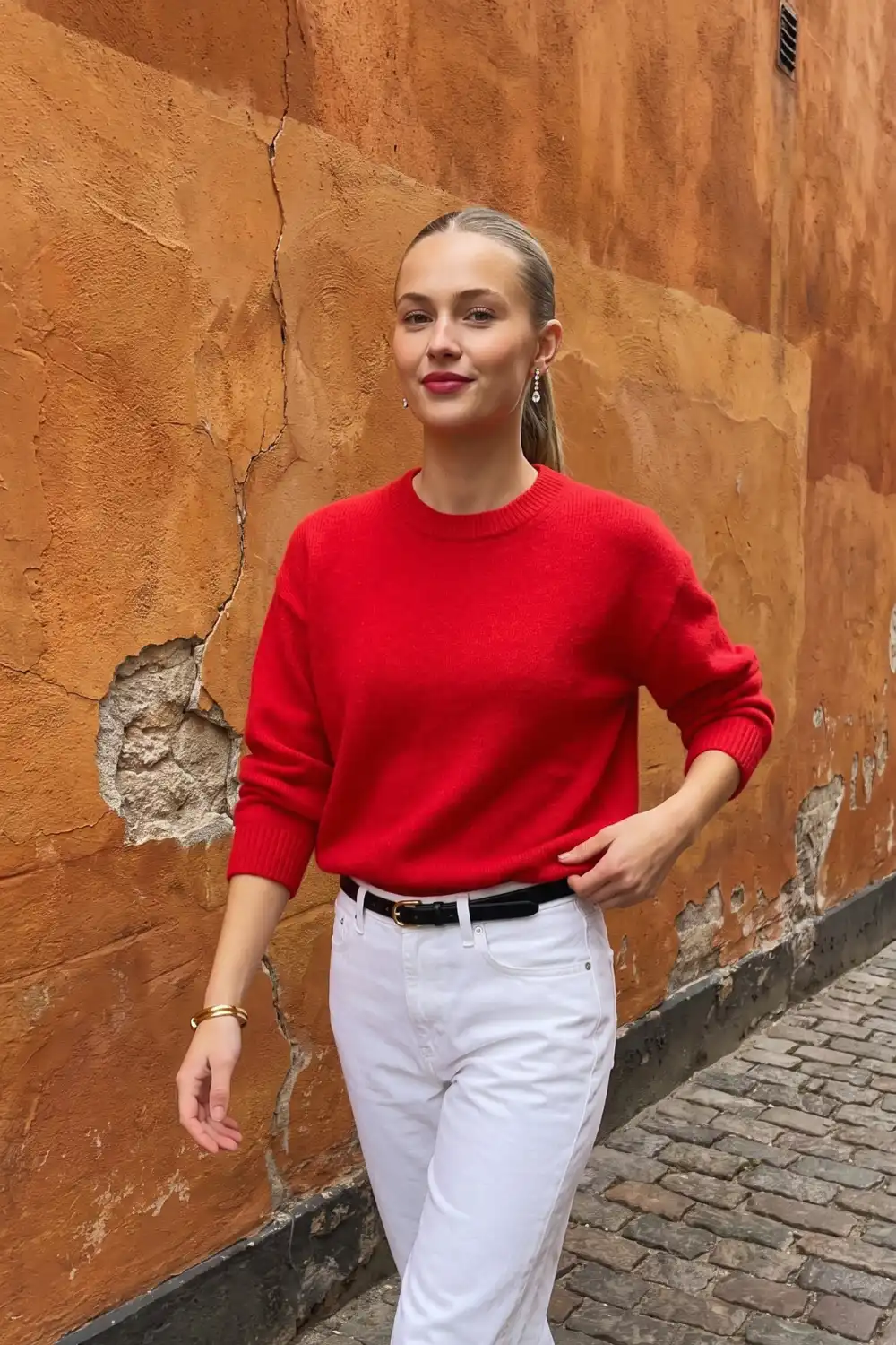 Woman in bright red crew neck knit sweater with white belted straight jeans