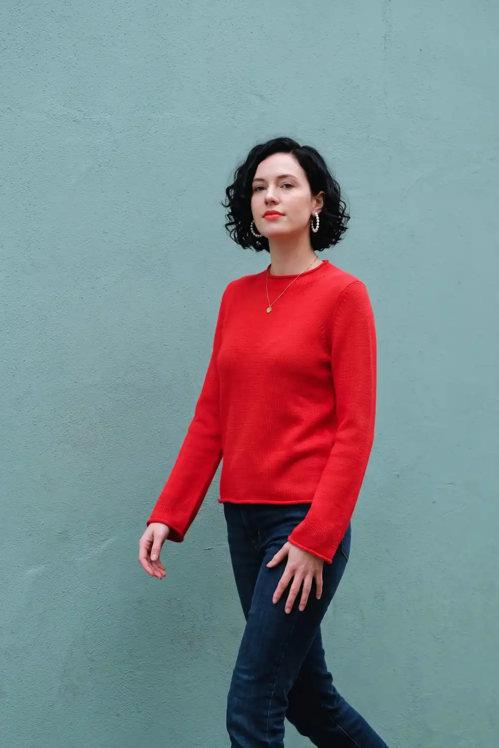 Woman in bright red fine knit crew neck sweater with dark wash skinny jeans