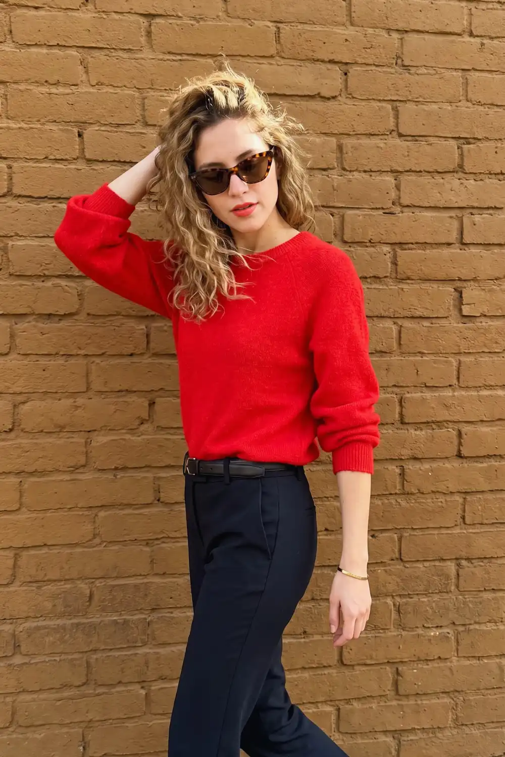 Woman in bright red fluffy crew neck knit sweater with navy belted straight trousers