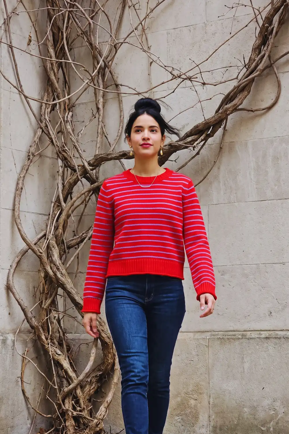 Woman in red lavender stripe cropped crew neck knit sweater with dark wash skinny jeans