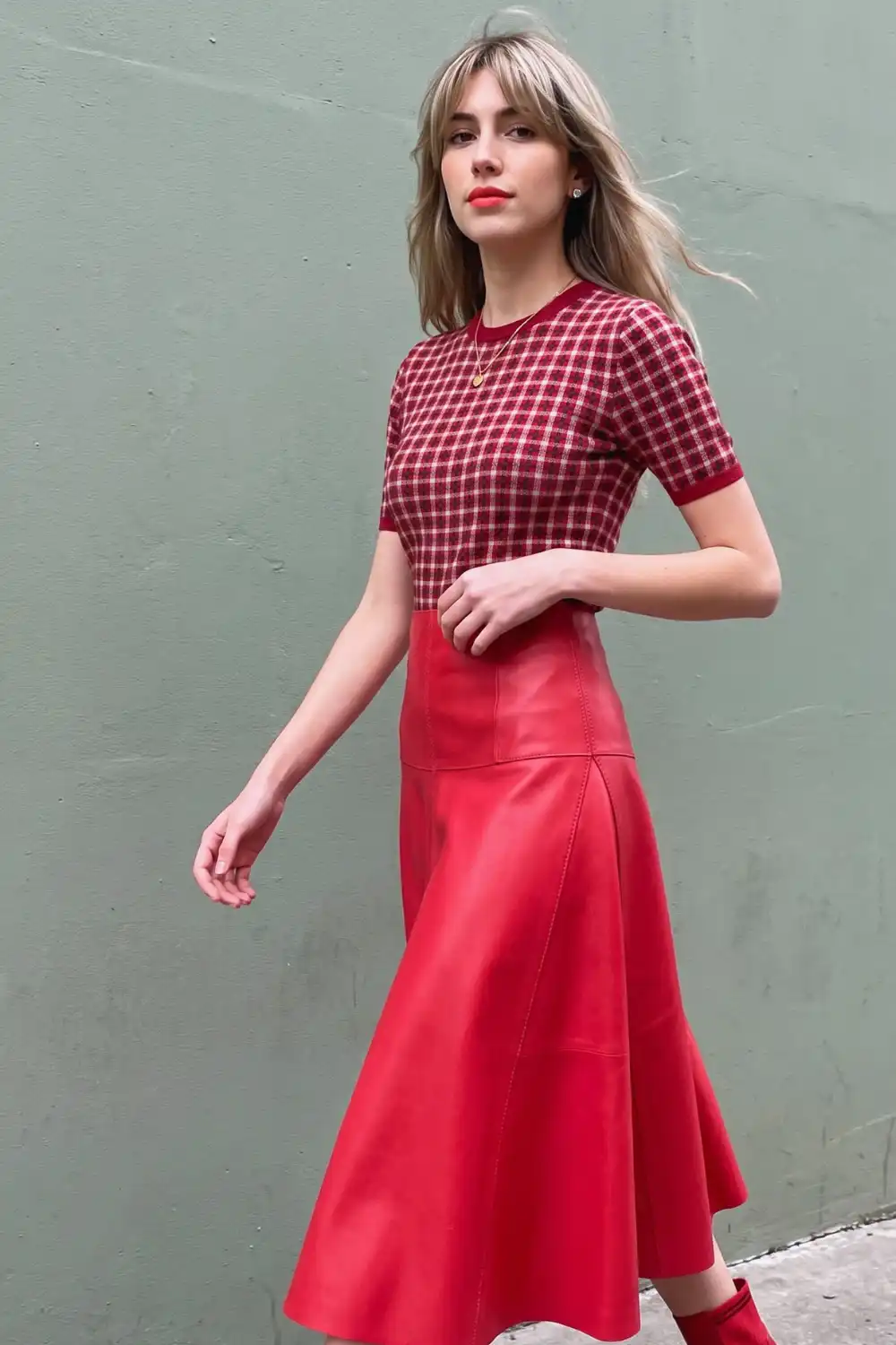 Woman in red plaid knit top with red leather flared midi skirt and red boots