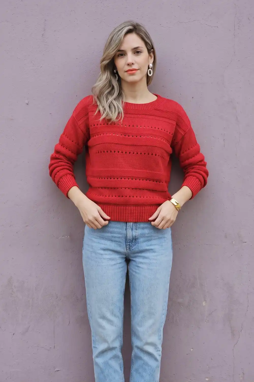Woman in red pointelle stripe textured crew neck knit sweater with light wash straight jeans