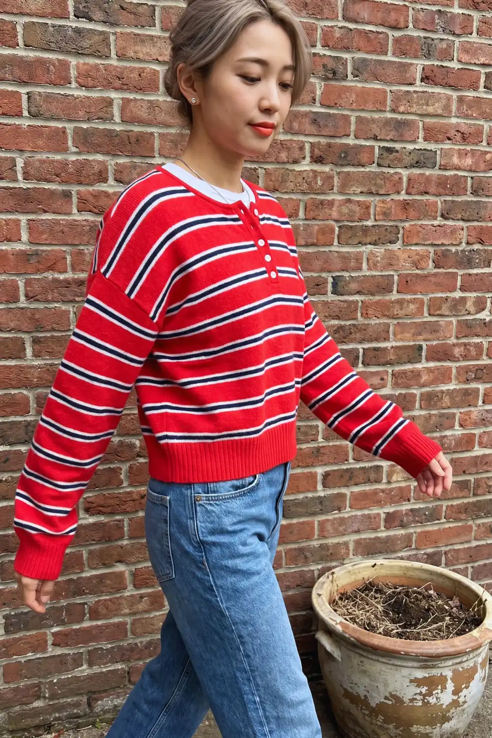 Woman in red navy white stripe henley knit sweater with light wash wide leg jeans