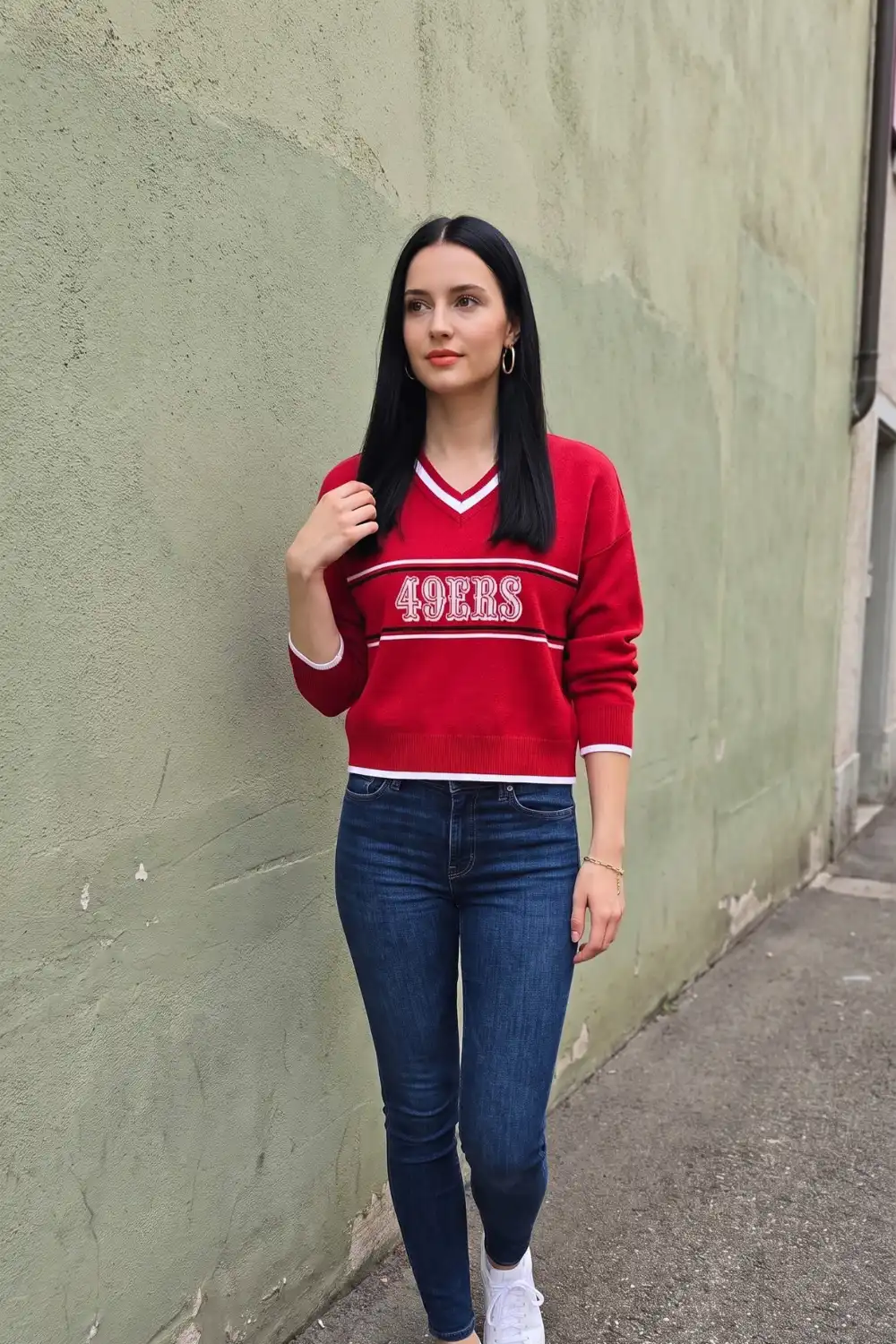 Woman in red white varsity v-neck graphic knit sweater with dark wash skinny jeans