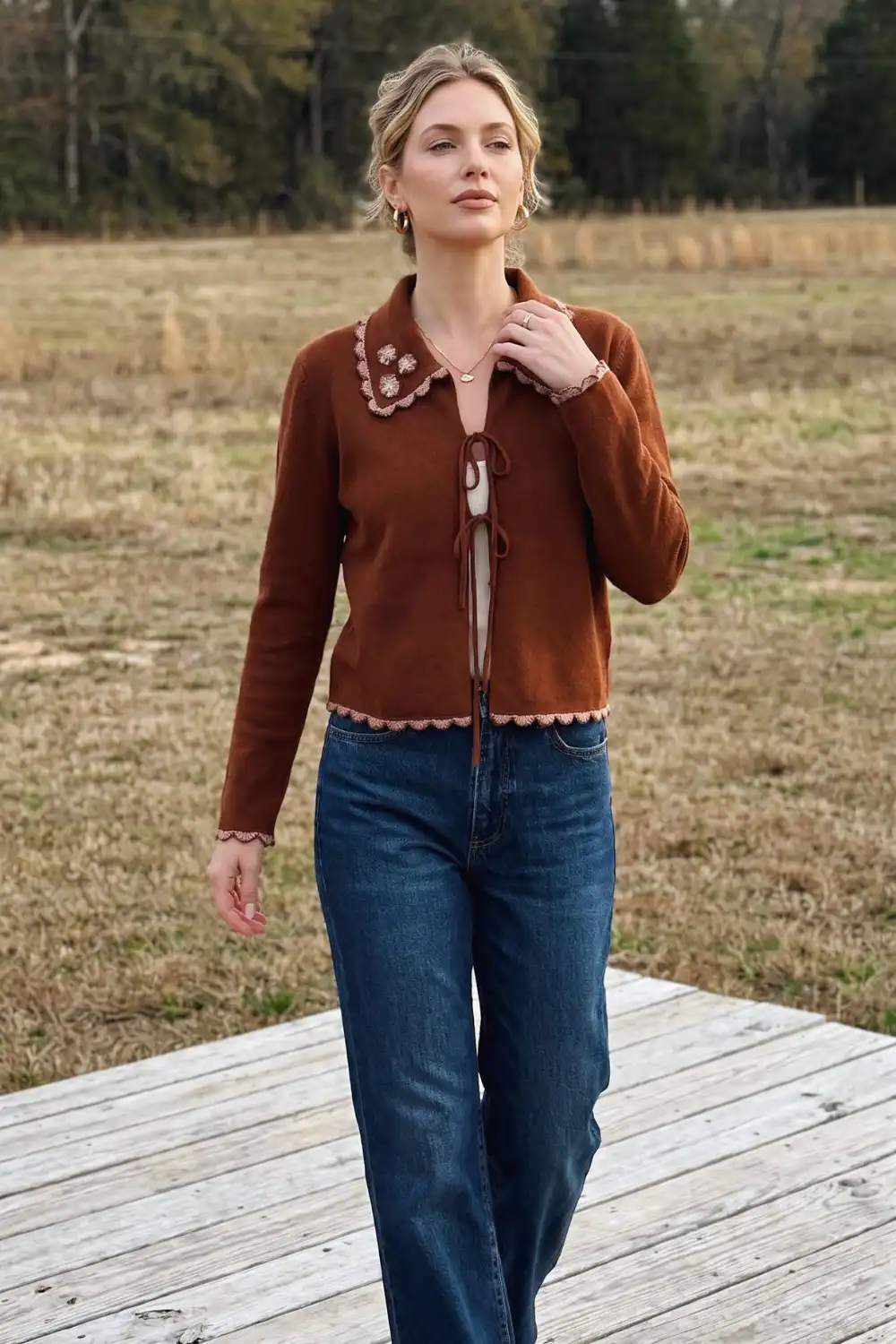 Woman in rust brown crochet trim tie-front collared knit cardigan with dark wash wide leg jeans