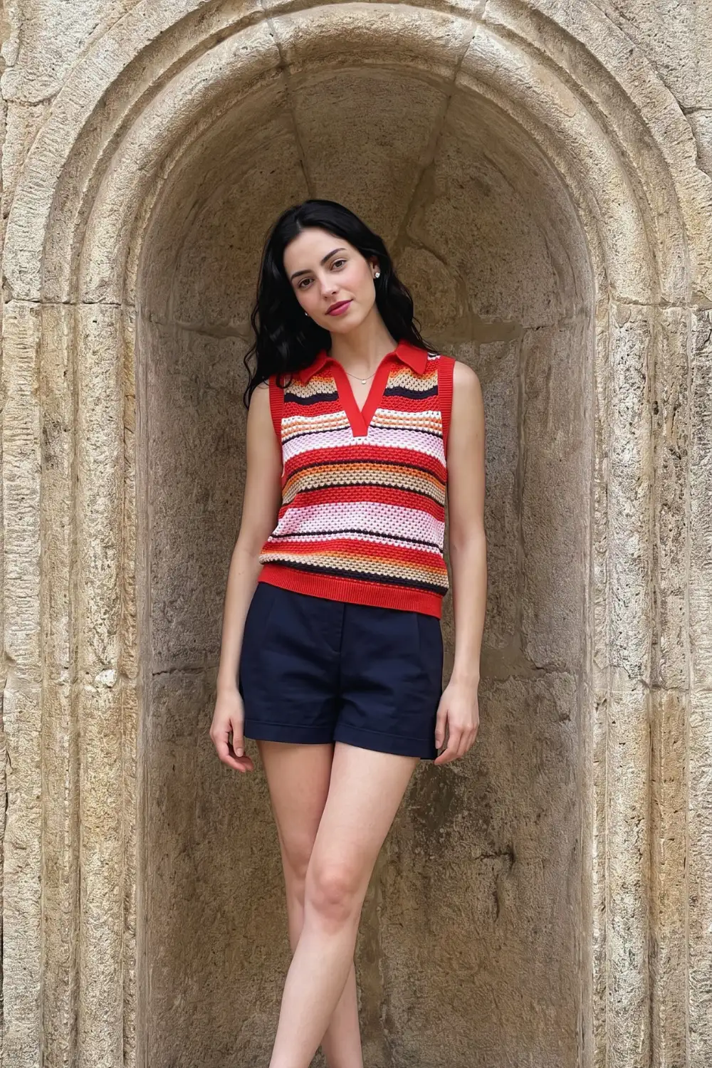 Woman in red multi colour stripe crochet polo collar knit vest with navy tailored shorts