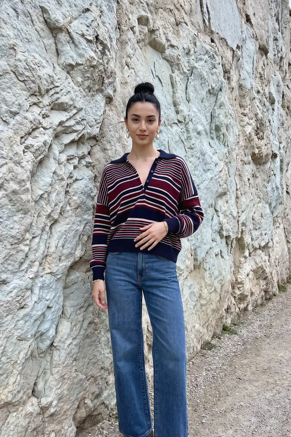 Woman in navy burgundy stripe collared polo oversized sweater with mid blue wide leg jeans