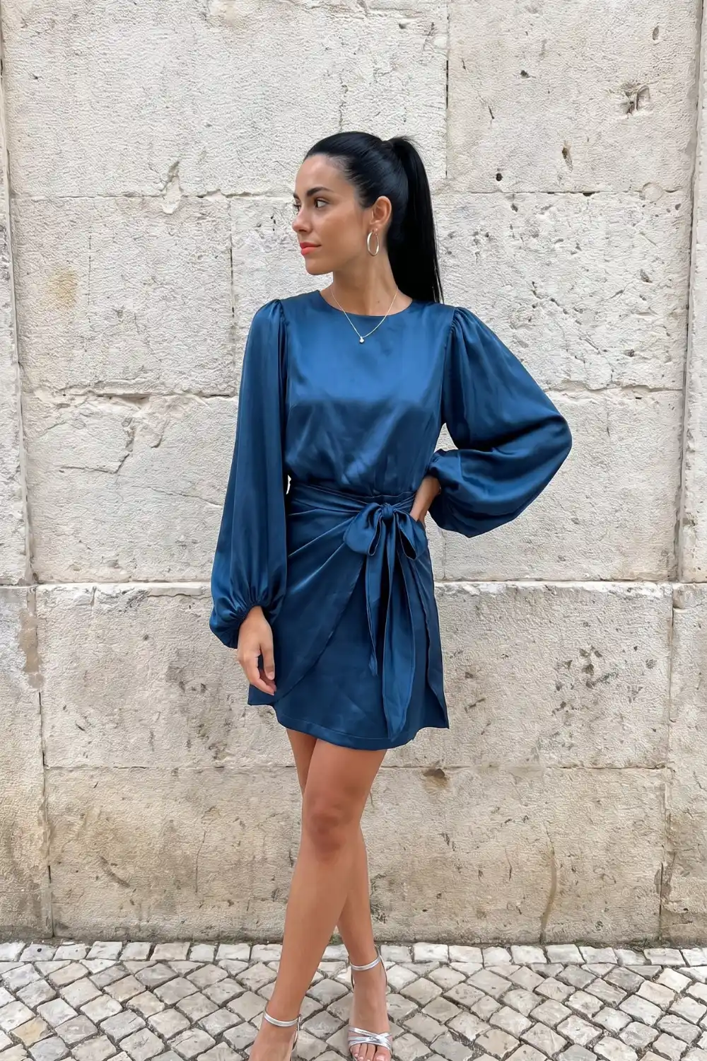 Woman wearing teal satin wrap mini dress with balloon sleeves