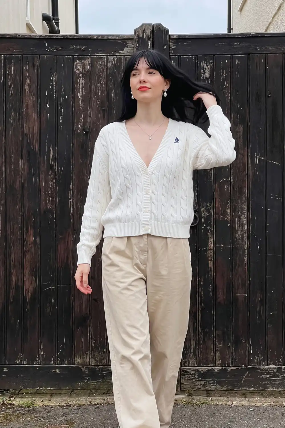 Woman in white cable knit v neck cardigan with beige wide leg chino trousers