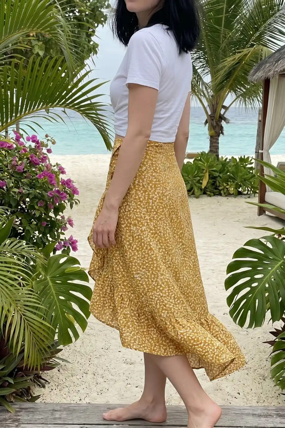 Woman wearing white fitted crop tee with mustard yellow ditsy floral wrap ruffle midi skirt at beach