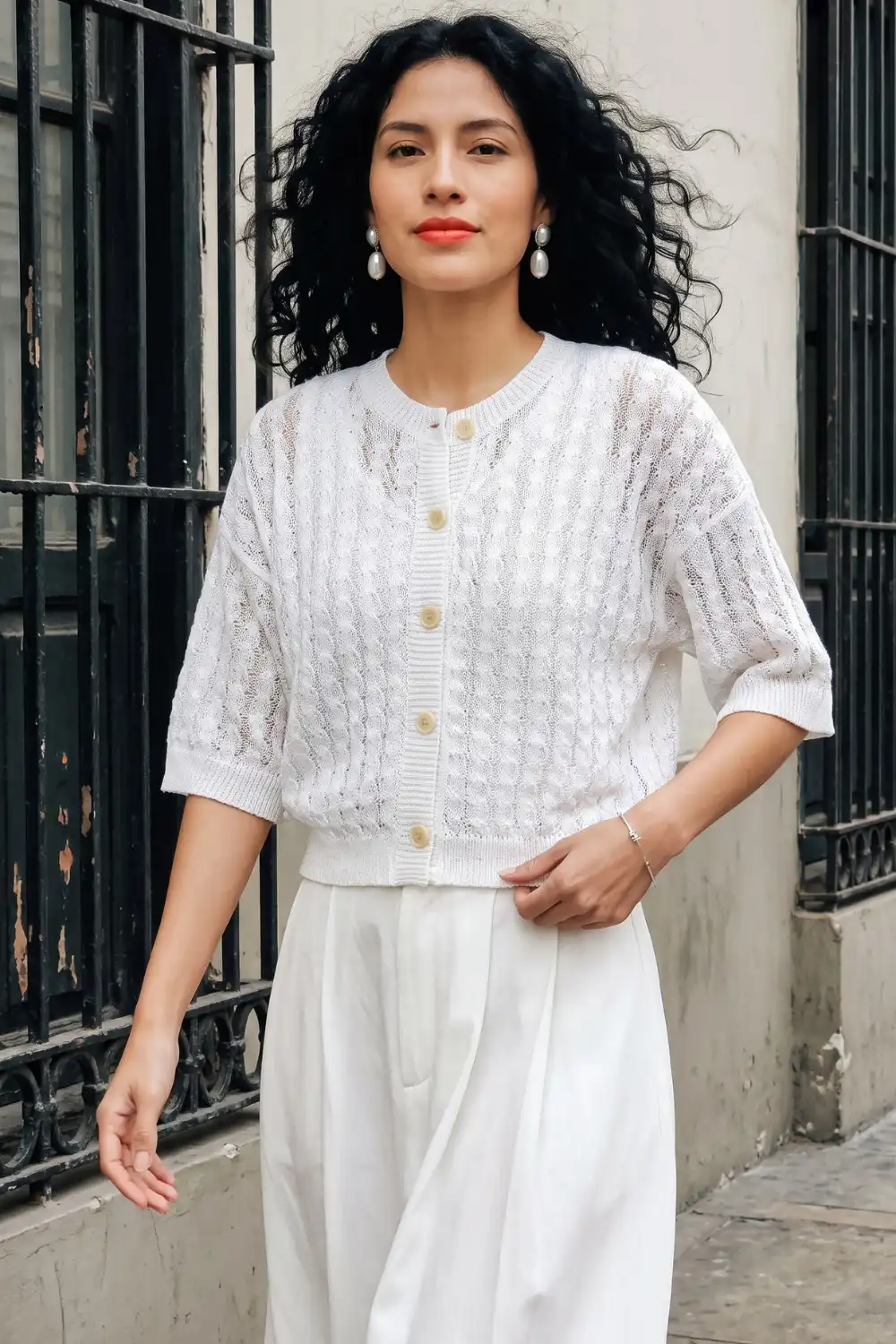 Woman in white short sleeve pointelle knit cardigan with white wide leg trousers
