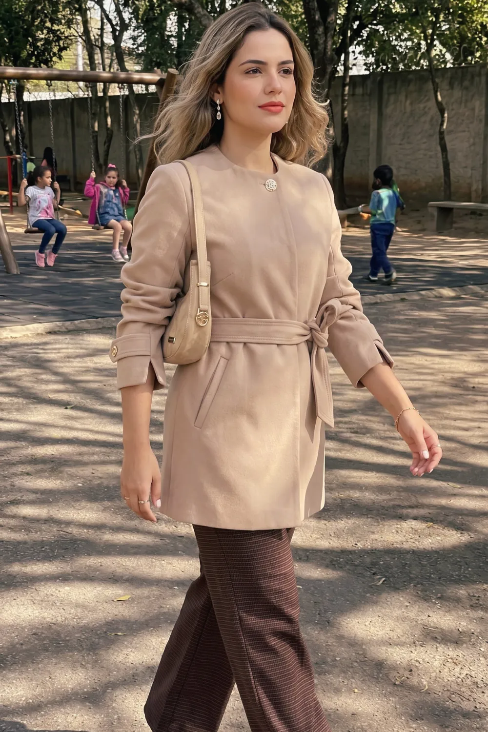 Woman in beige belted wool coat with brown plaid trousers
