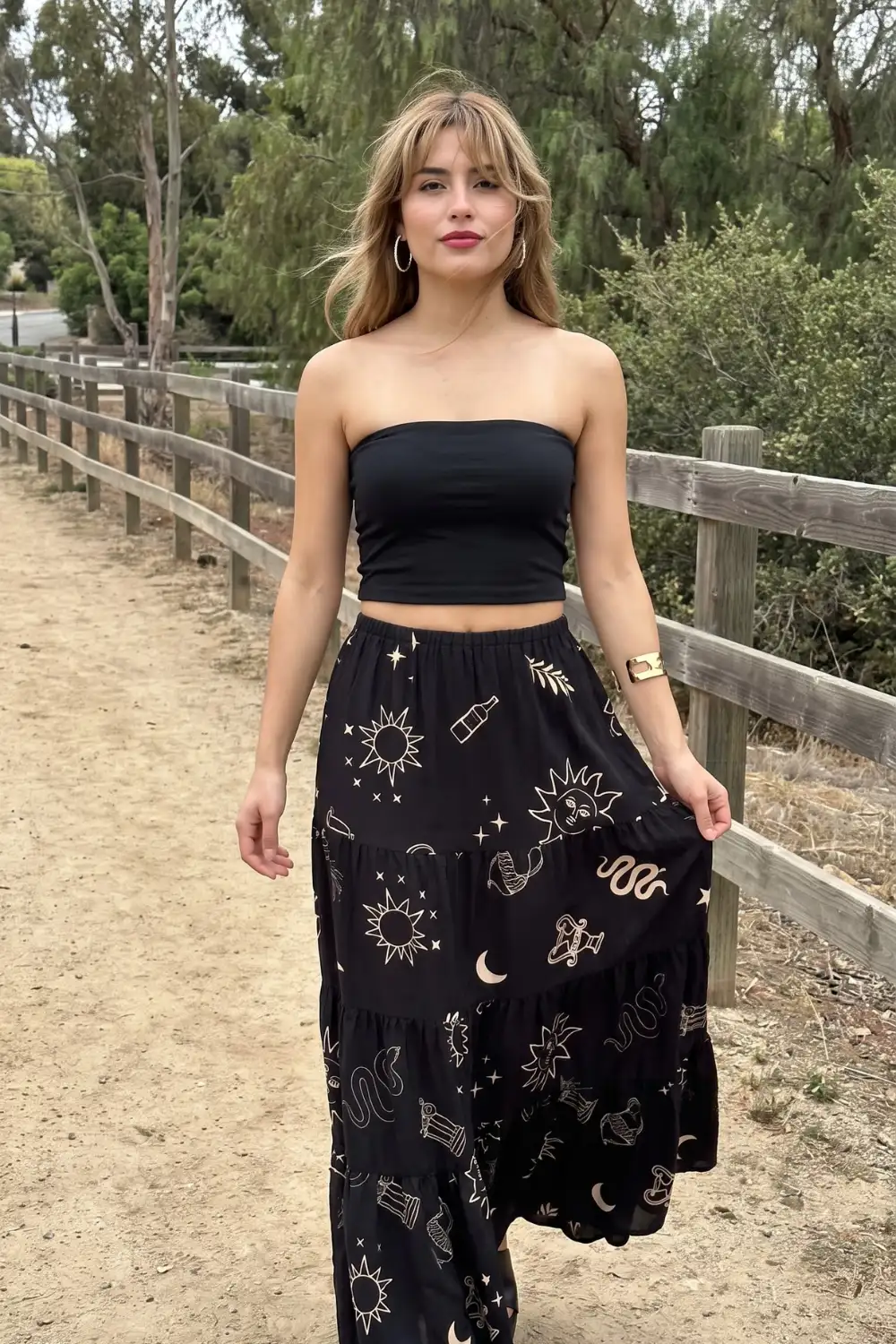 Woman in black strapless bandeau crop top with black celestial print tiered maxi skirt