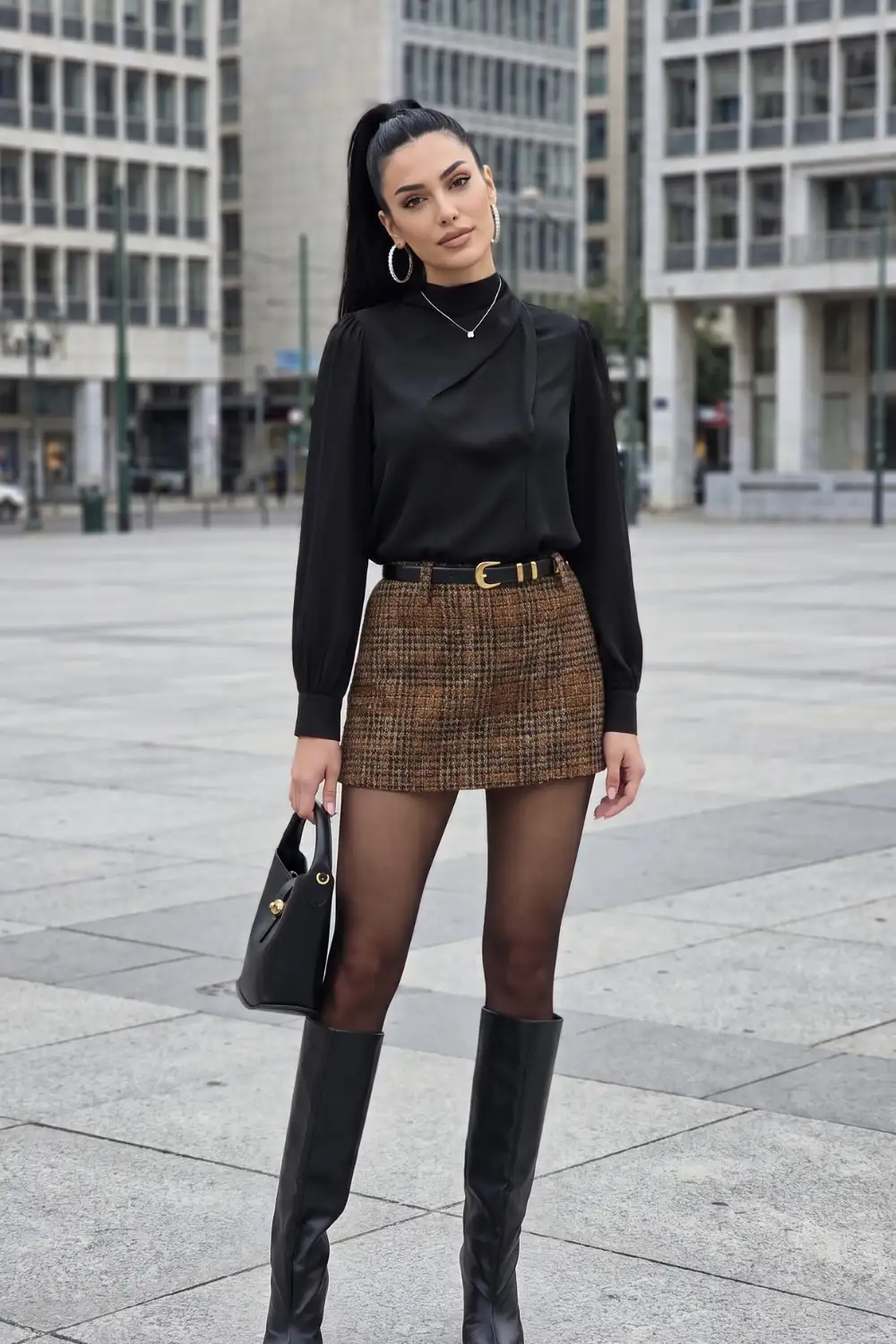 Woman in black satin blouse with brown tweed plaid mini skirt and black knee high boots