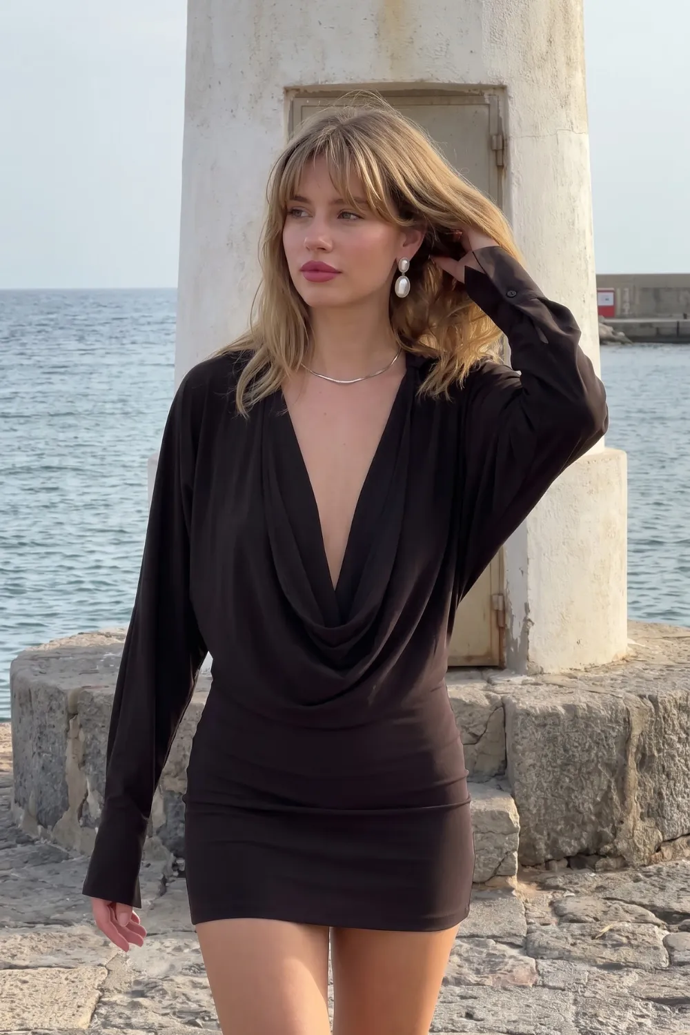 Woman in black cowl neck draped long sleeve mini dress