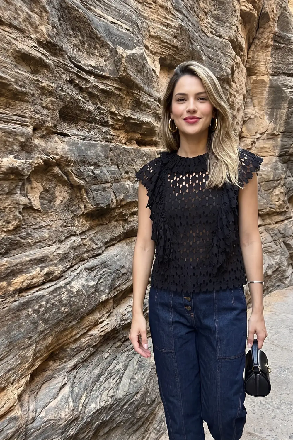 Woman in black tiered fringe eyelet lace sleeveless top with dark navy wide leg jeans