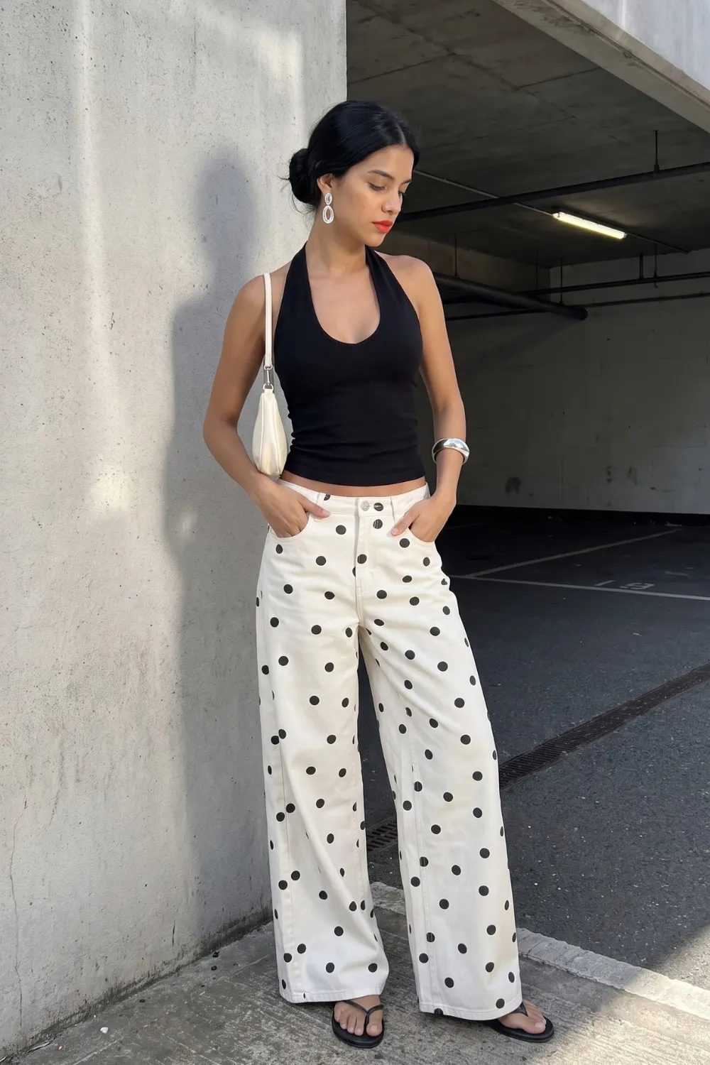 Woman in black halter neck crop top with cream black polka dot wide leg jeans