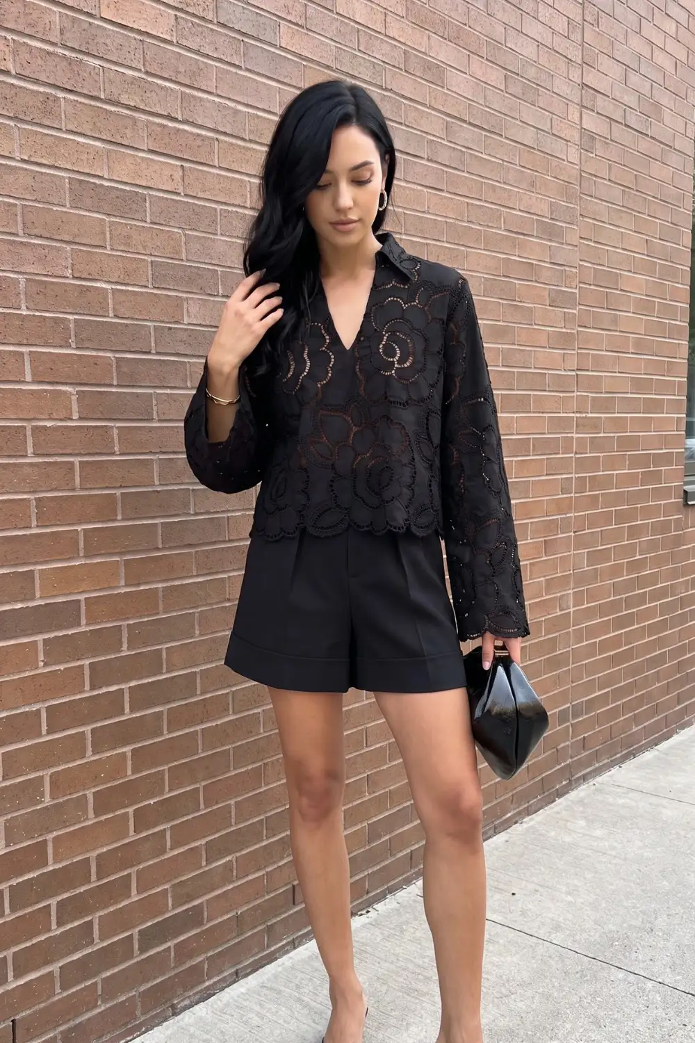 Woman in black floral lace collared crop blouse with black tailored shorts